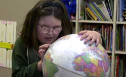 Young blind girl in classroom exploring a brailled globe