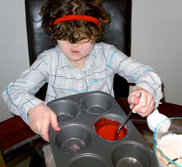 Blind girl mixes the red scented paint in a muffin tin