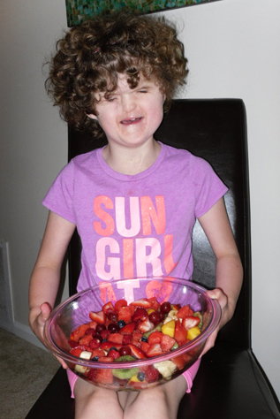 Blind girl had made a fruit salad and holds it in a bowl on her lap