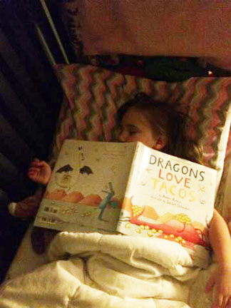Girl asleep with Dragons book over her face