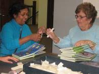 Picture of two volunteers putting labels on a children's board book.