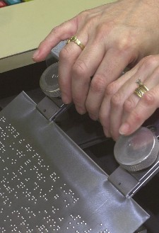 A zinc plate is removed from a plate embossing device after being embossed with braille