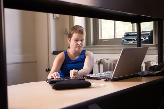 Proofreader in front of computer laptop and braille notetaker