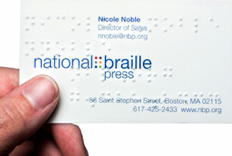 Hand holding a braille embossed NBP business card.