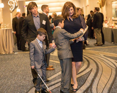 well-dressed family of four with a blind boy at the gala.