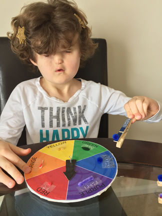 Girl holding blue game piece, about to clip it to color wheel