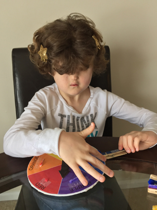 Girl attaches blue game piece to color wheel