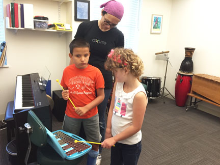 Blind boy and girl, with parent, play with xylophone in music room.